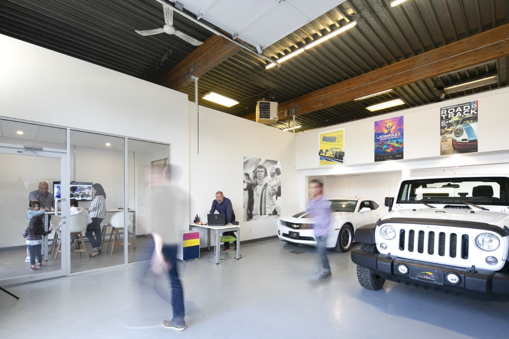 Inside the CredRev and Company of Cars shop in Kelowna, with vehicles on the floor and a family meeting in the office beyond